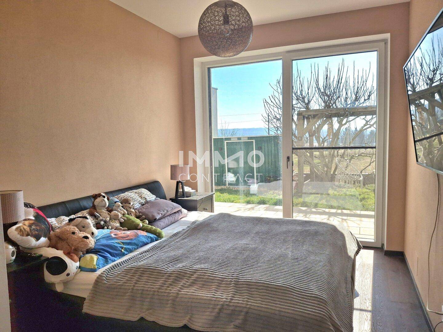 Schlafzimmer mit Doppelbett, Terrassenzugang und Blick auf den Garten.