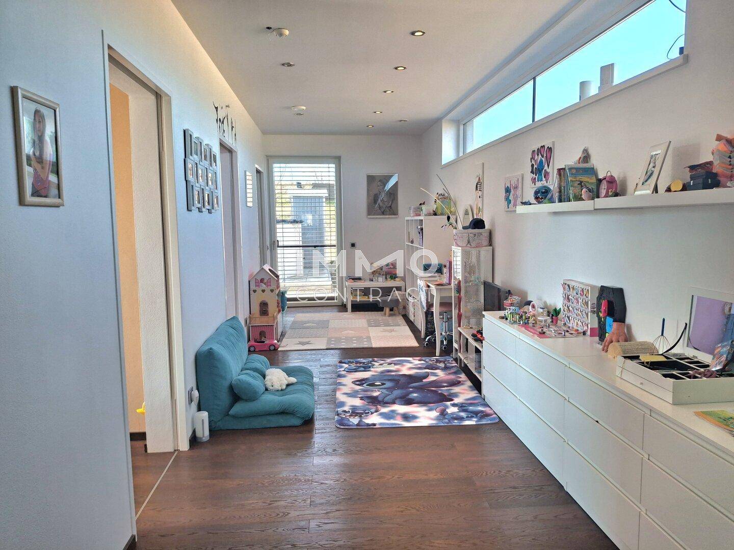 Langer, heller Flur mit Holzboden und Spielbereich für Kinder, gut beleuchtet.