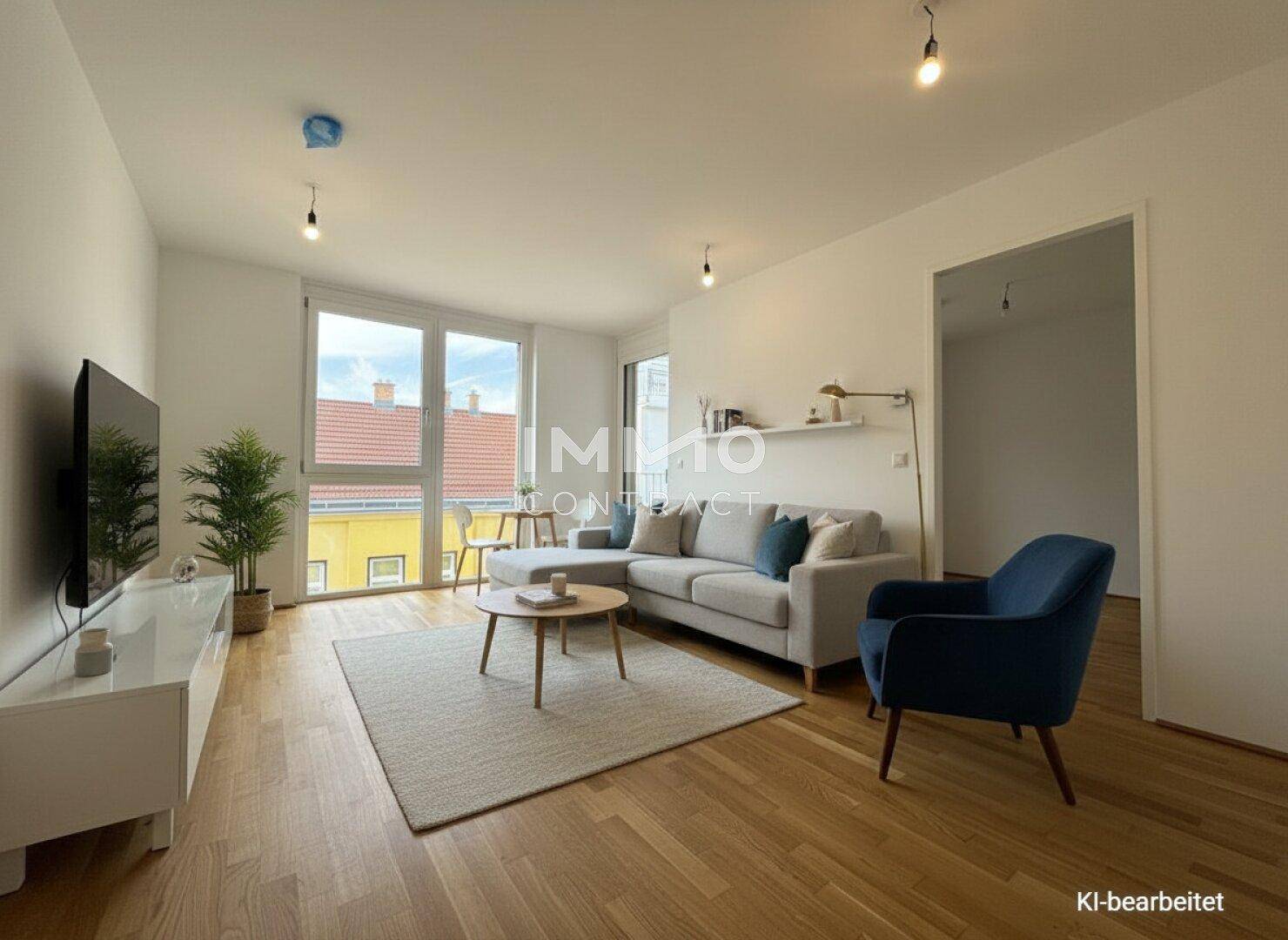Helles Wohnzimmer mit bequemer Couch, Holzboden und Zugang zum Balkon.