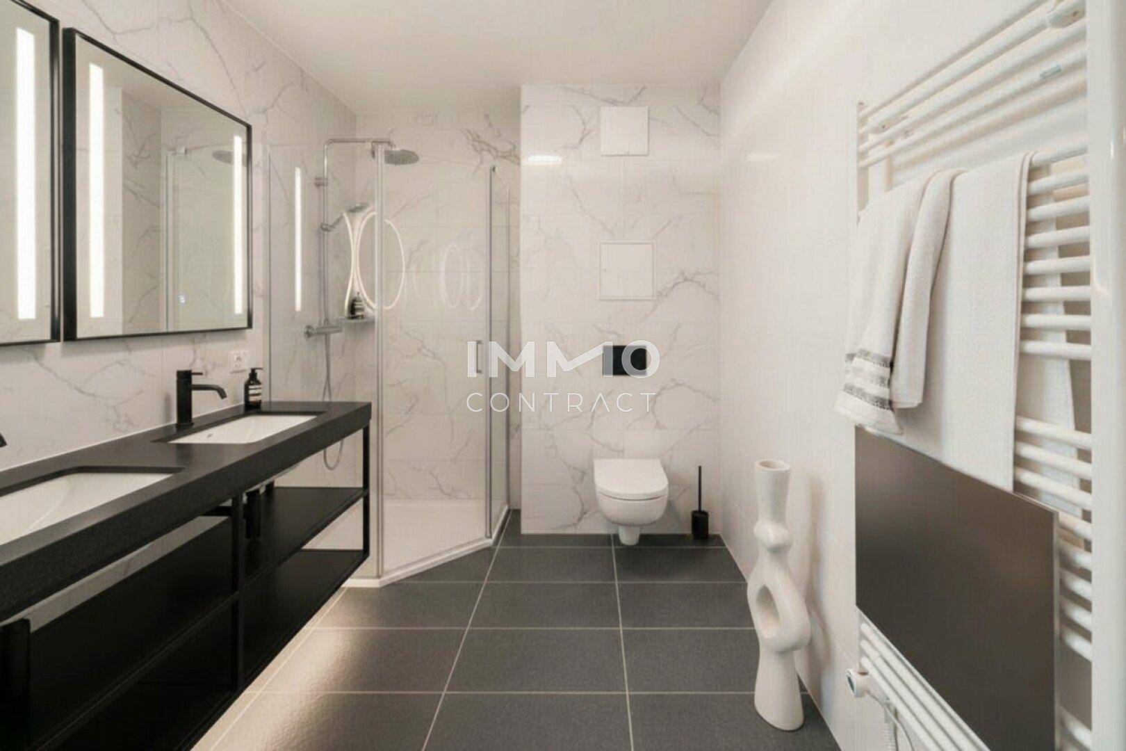 Modernes Badezimmer mit doppelten Waschbecken, großer Dusche und Marmorfliesen.