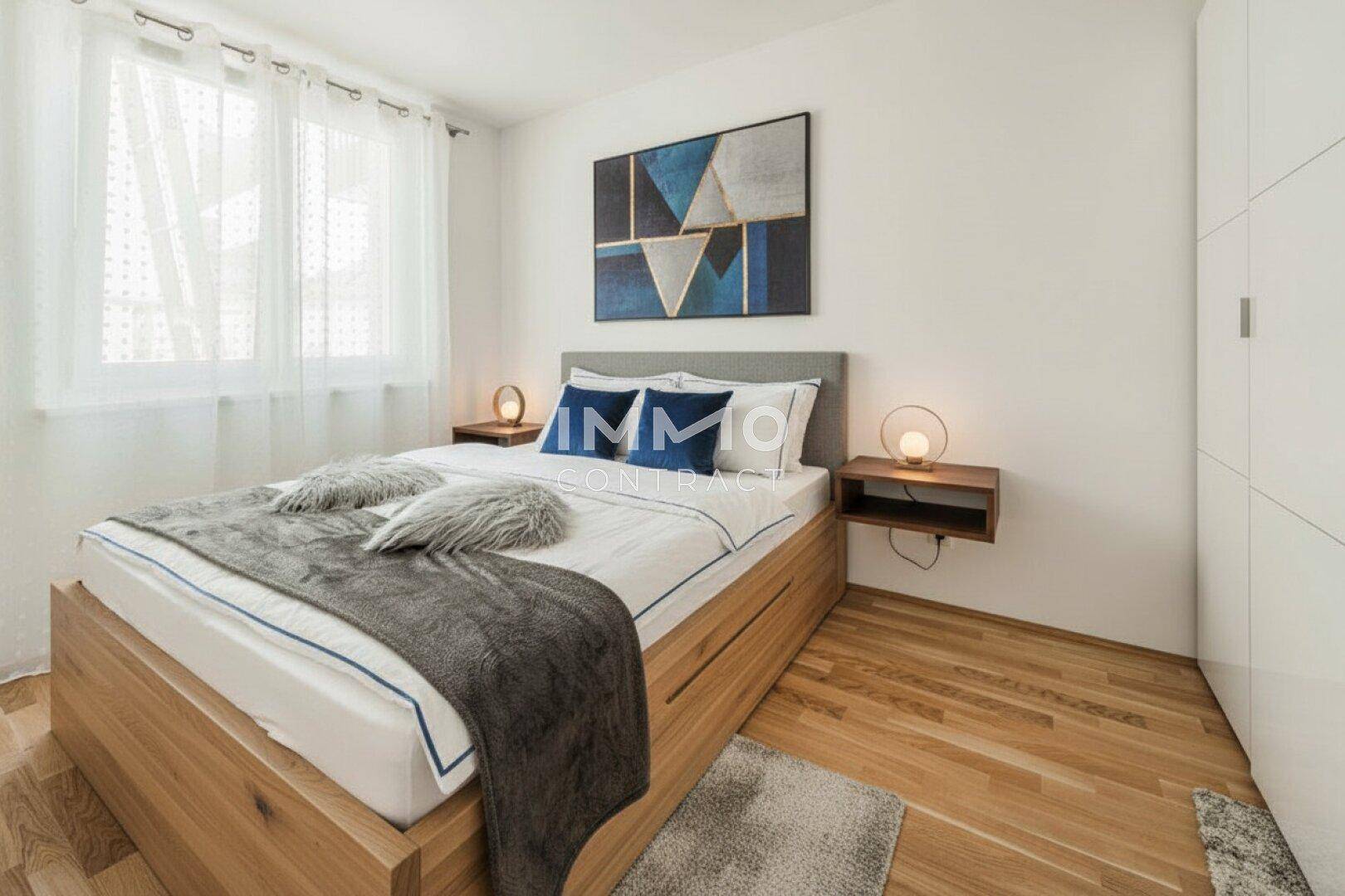 Gemütliches Schlafzimmer mit Holzbett, Parkettboden und großen Fenstern für viel Tageslicht.