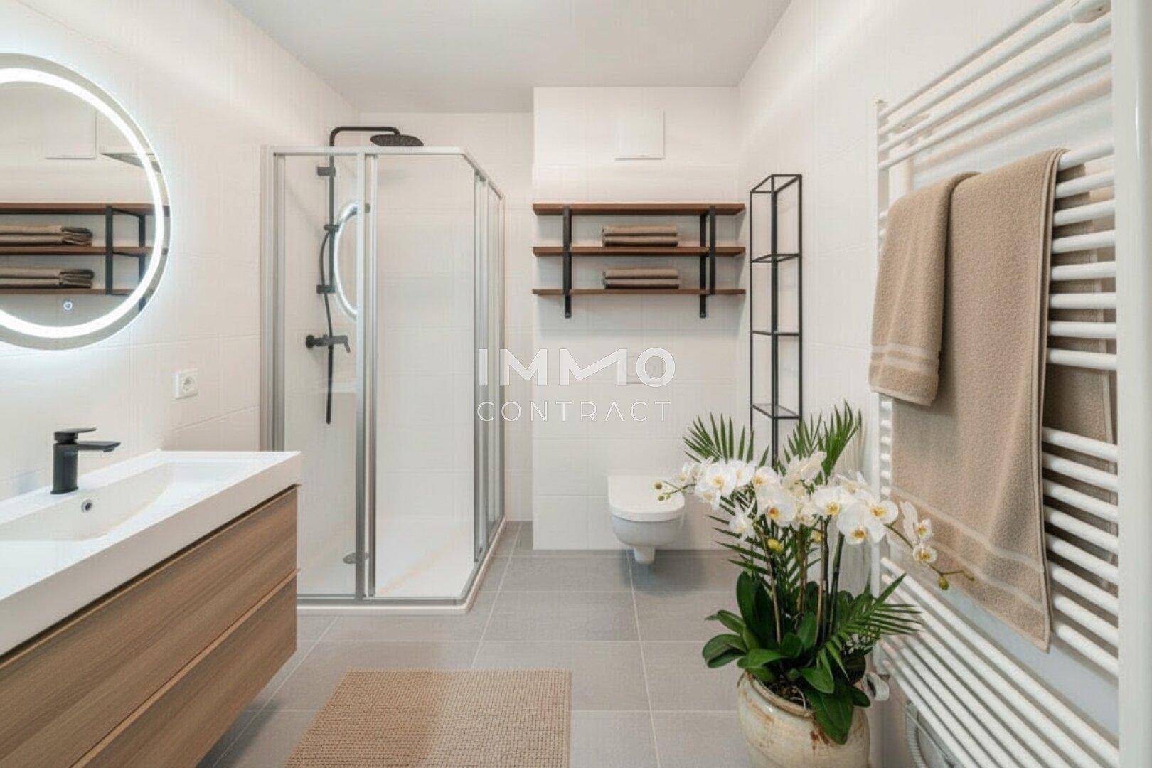 Modernes Badezimmer mit ebenerdiger Dusche, elegantem Waschtisch und beheiztem Handtuchhalter.
