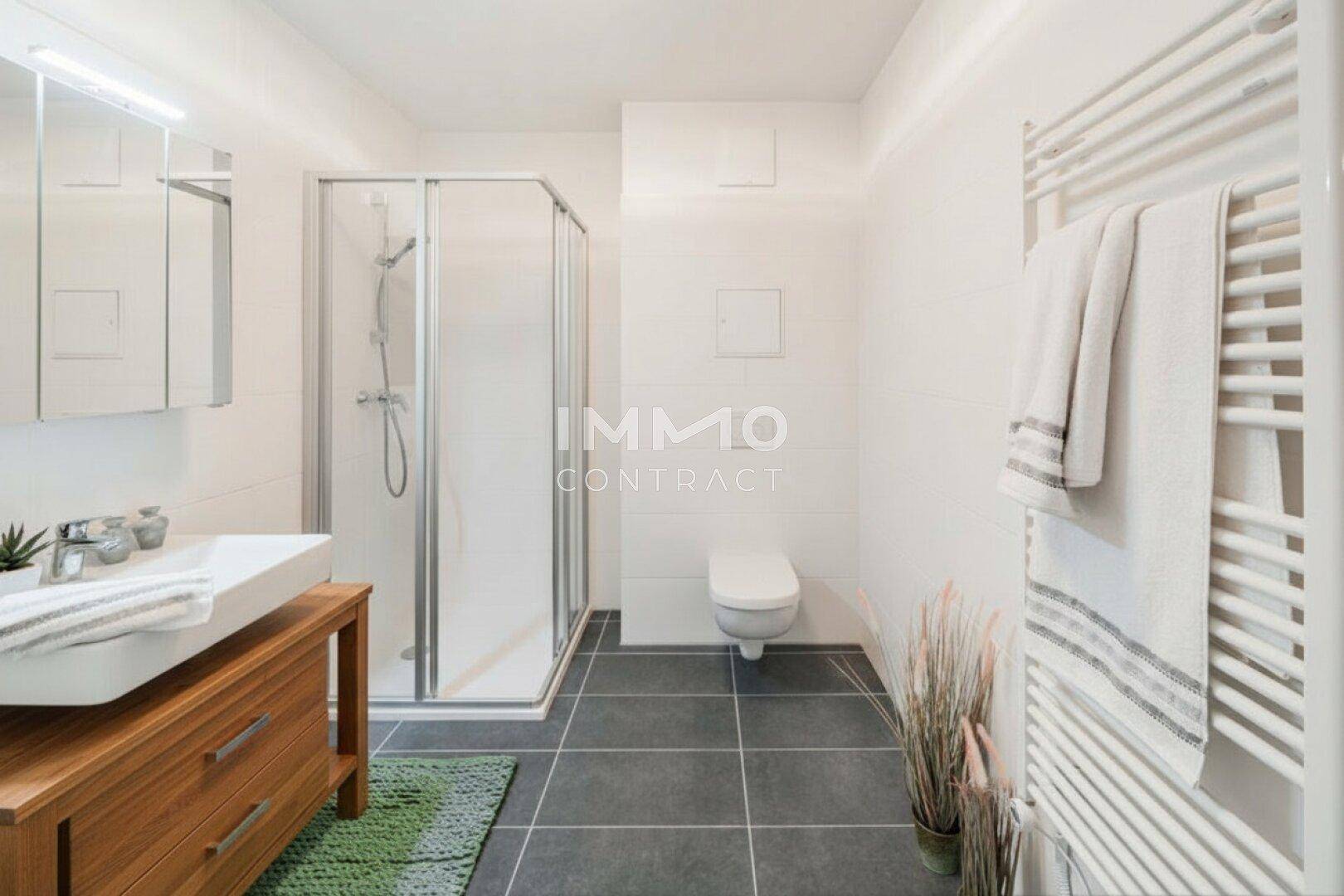Modernes Badezimmer mit Duschkabine, wandhängendem WC und einem praktischen Handtuchheizkörper.