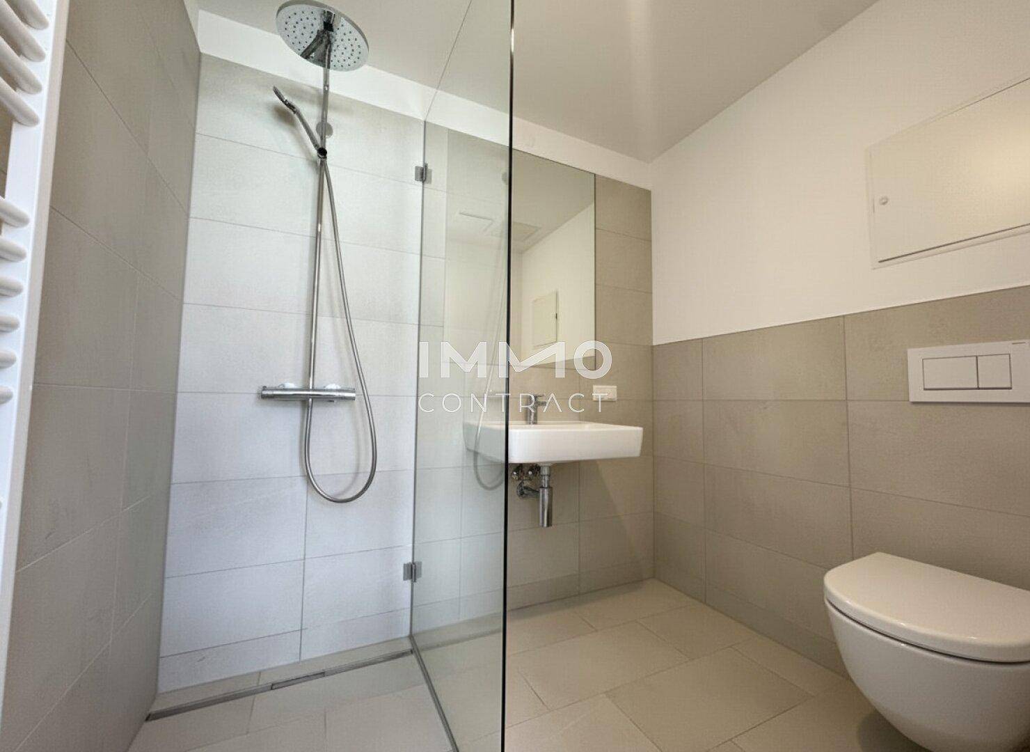 Helles Badezimmer mit ebenerdiger Dusche, Wand-WC und modernem Waschbecken in neutralen Farben.
