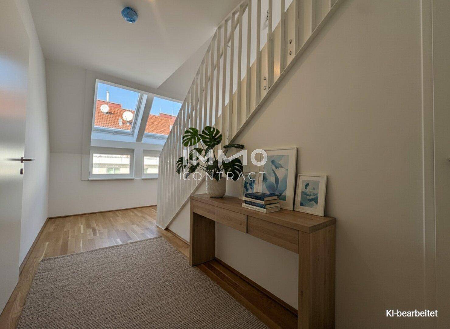 Heller Flurbereich mit Holztreppe, modernem Konsolentisch und großen Dachfenstern im Obergeschoss.