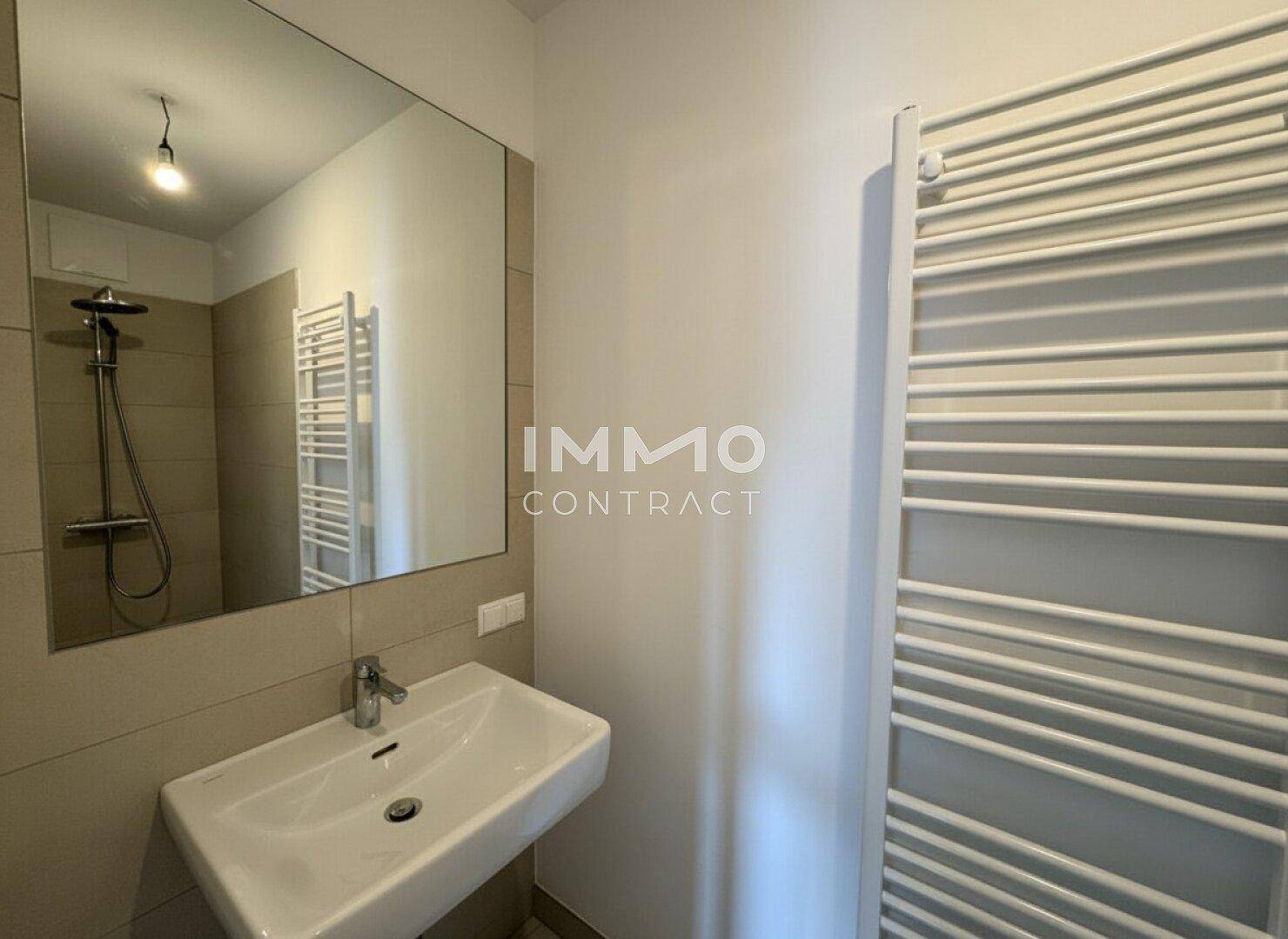 Helles Badezimmer mit modernem Waschbecken, großem Spiegel und beheiztem Handtuchhalter.