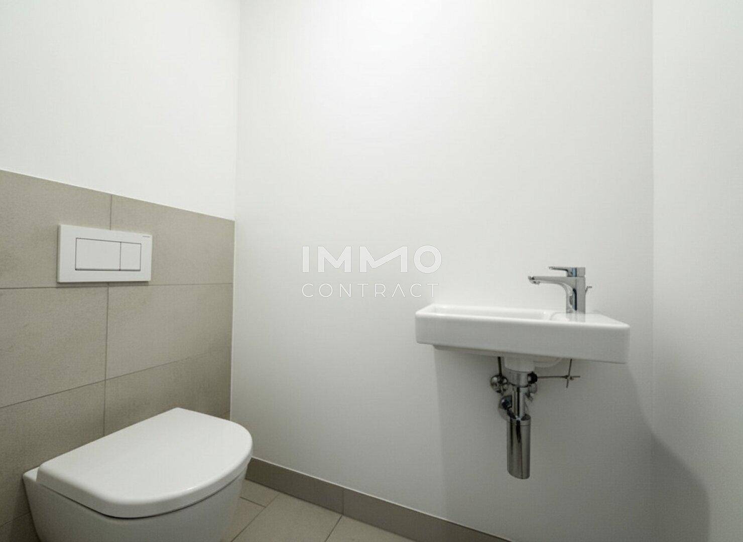 Kompaktes Gäste-WC mit Wand-WC und kleinem Waschbecken, halbhoch gefliest.