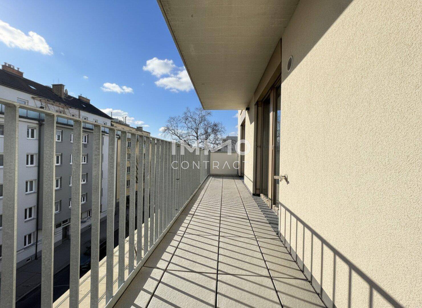 Sonniger Balkon mit Fliesenboden und Blick auf die umliegenden Gebäude und die Straße.
