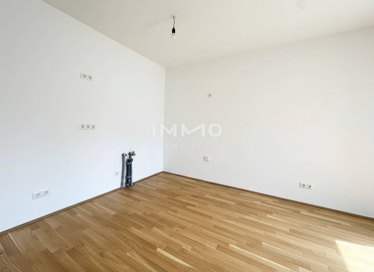 Leerer Küchenbereich mit Anschlüssen für eine Einbauküche und Holzboden.