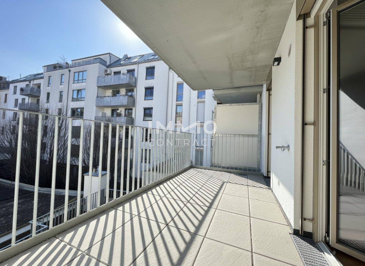 Heller Balkon mit Fliesenboden und Blick auf die umliegenden Gebäude.