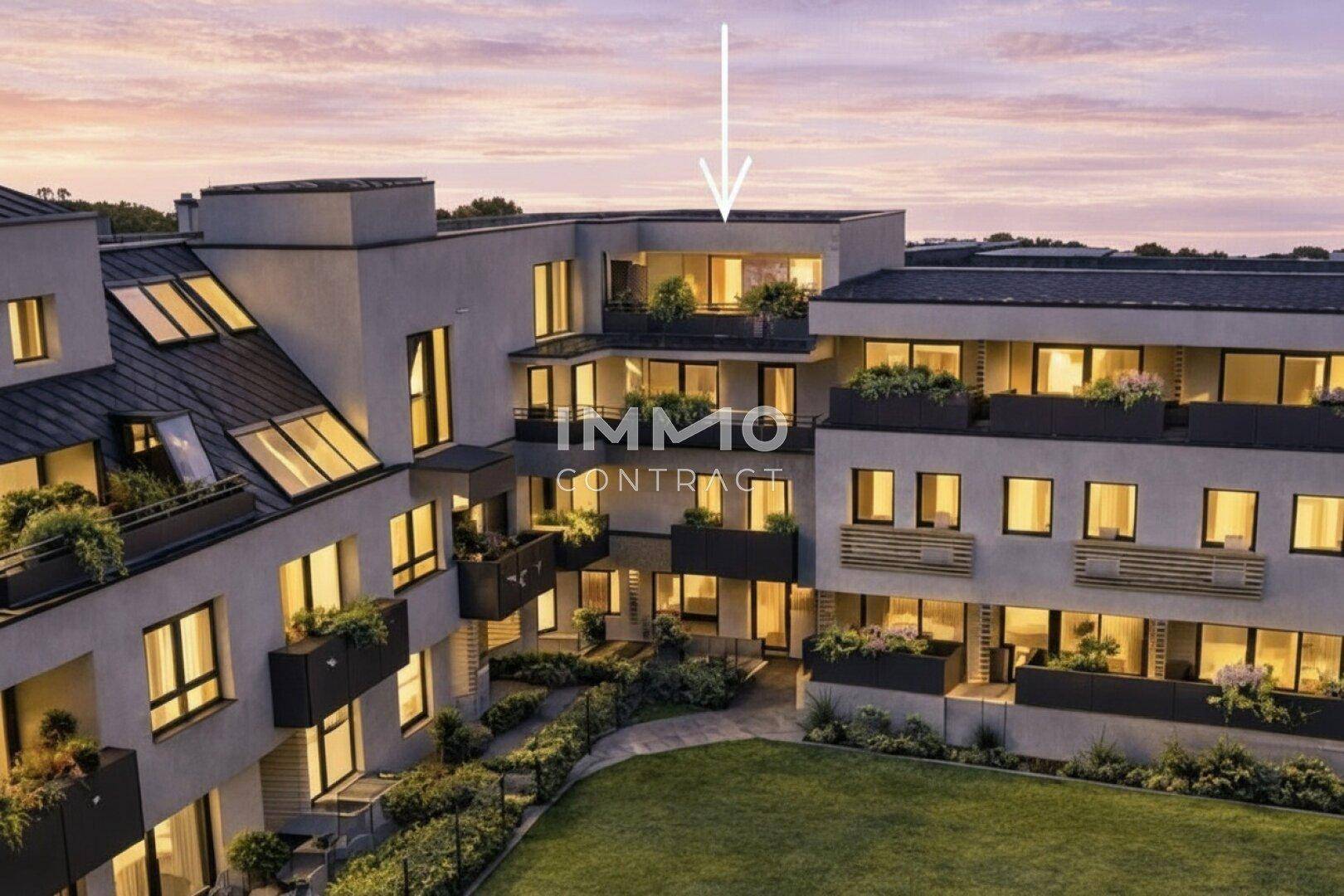 Moderne Wohnanlage mit Balkonen, Dachfenstern und gepflegter Grünfläche im Innenhof bei Sonnenuntergang.