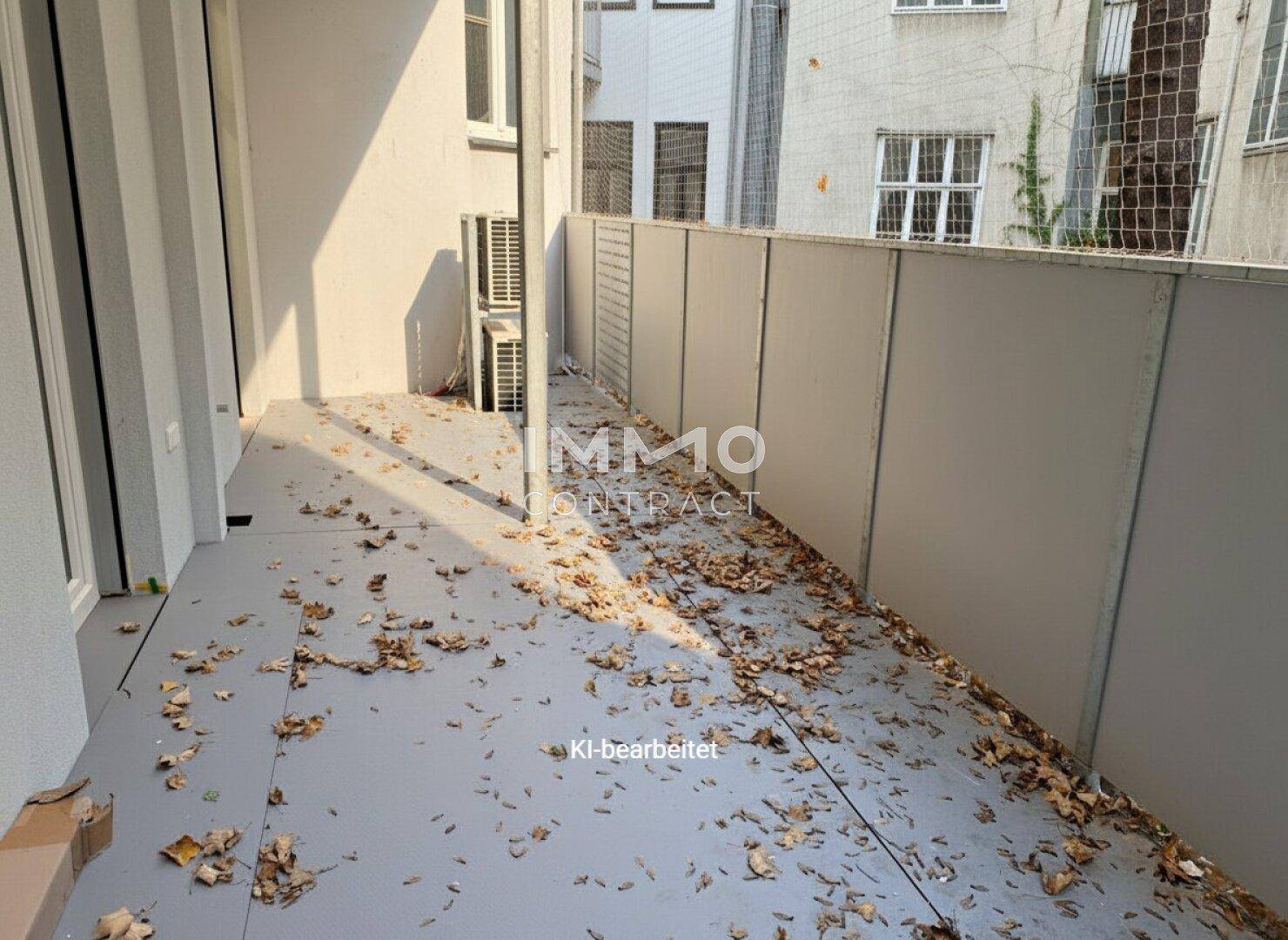 Langer, schmaler Balkon mit grauem Boden und Blick auf die umliegenden Gebäude.