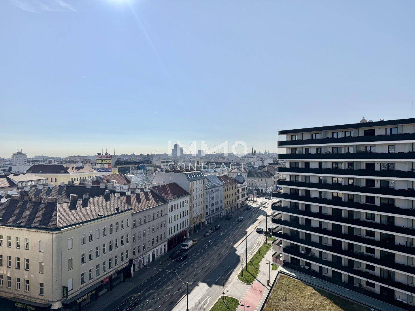 Weitläufiger Blick über die Stadt mit historischen Gebäuden und moderner Architektur unter blauem Himmel.
