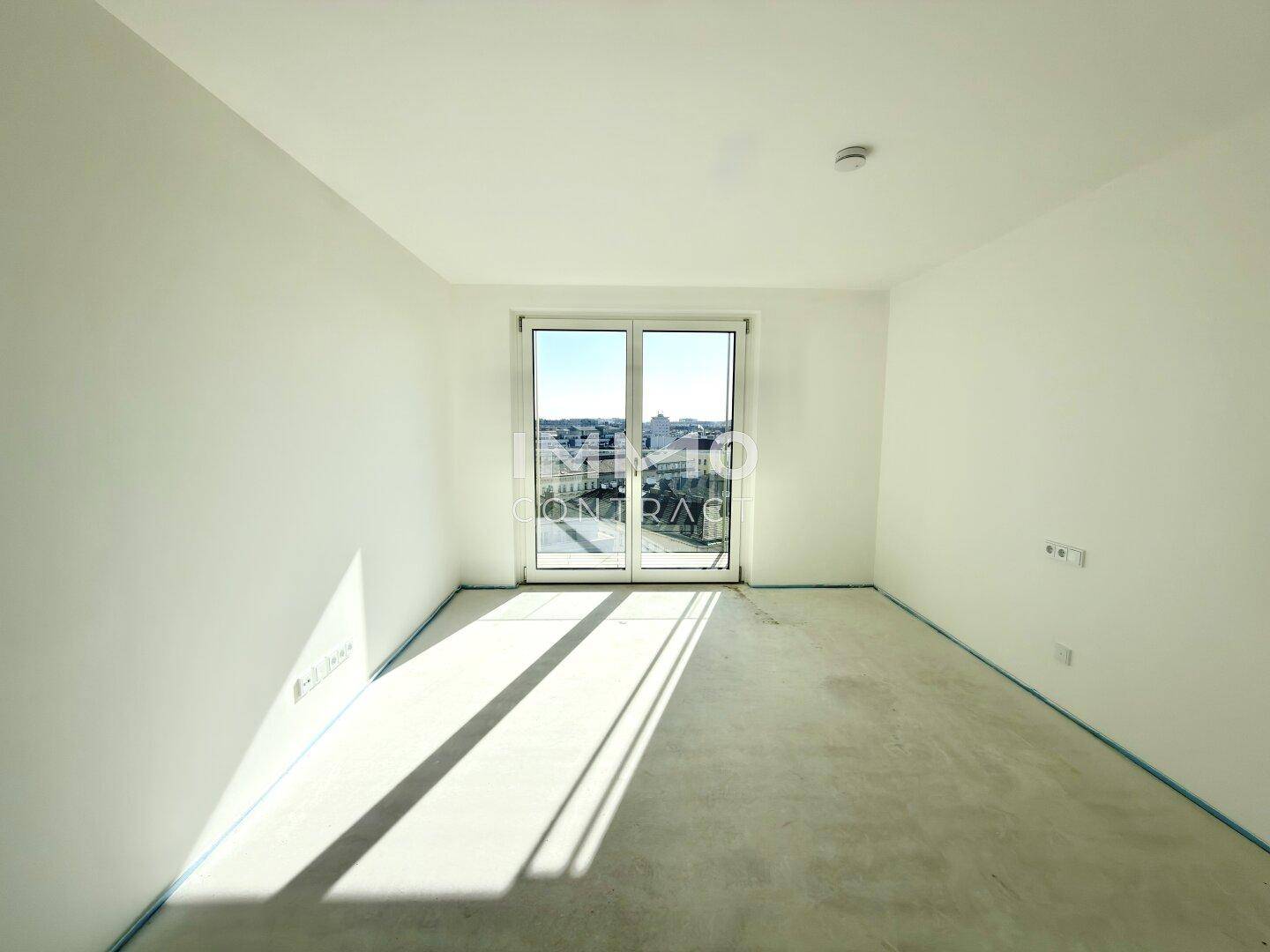 Unmöbliertes Zimmer mit großen Fenstern und Zugang zu einem französischen Balkon, ideal für Schlafzimmer oder Büro.