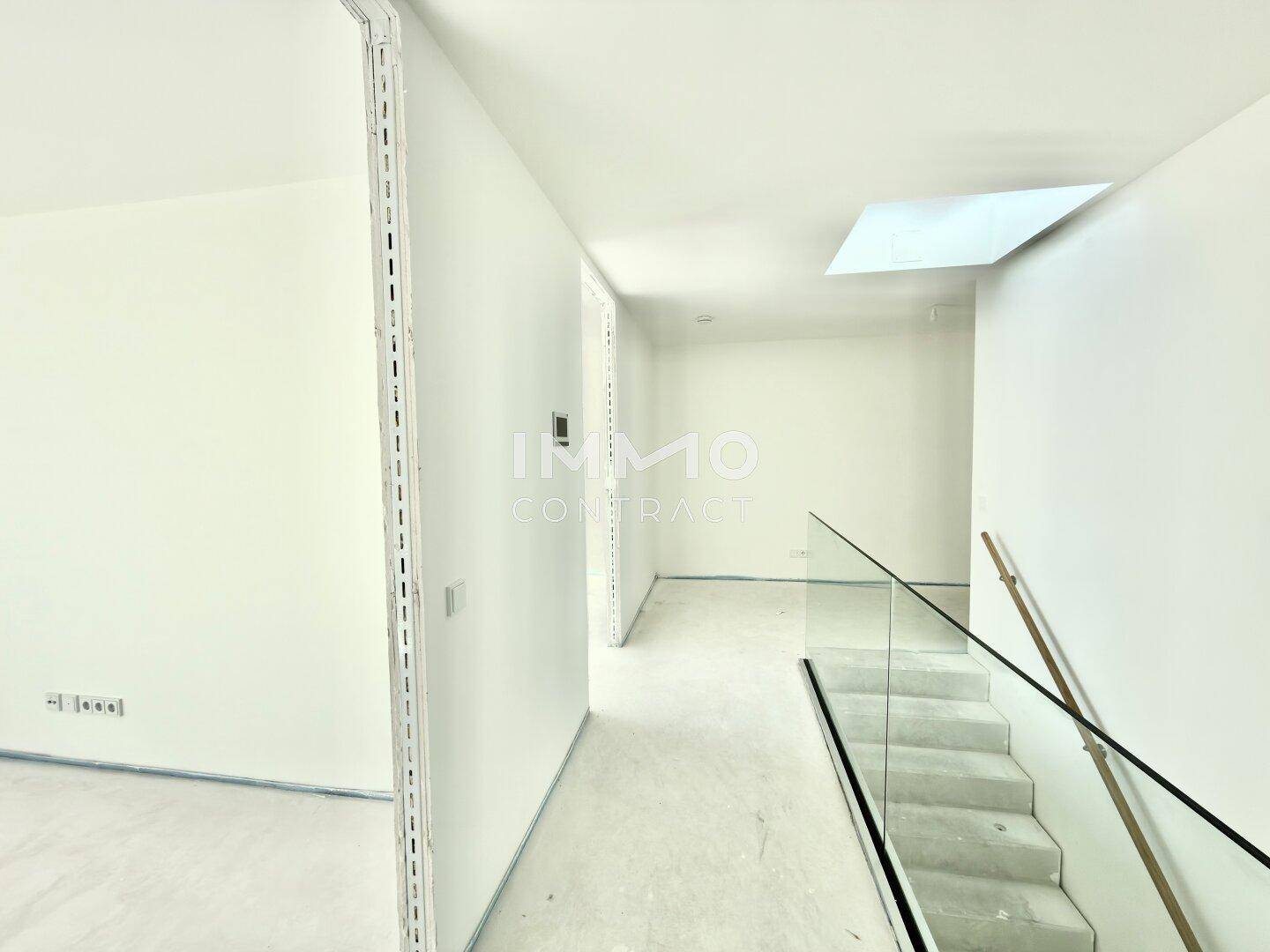 Lichtdurchfluteter Flur mit moderner Glasbrüstung, Treppe und Oberlicht für zusätzliches Tageslicht.