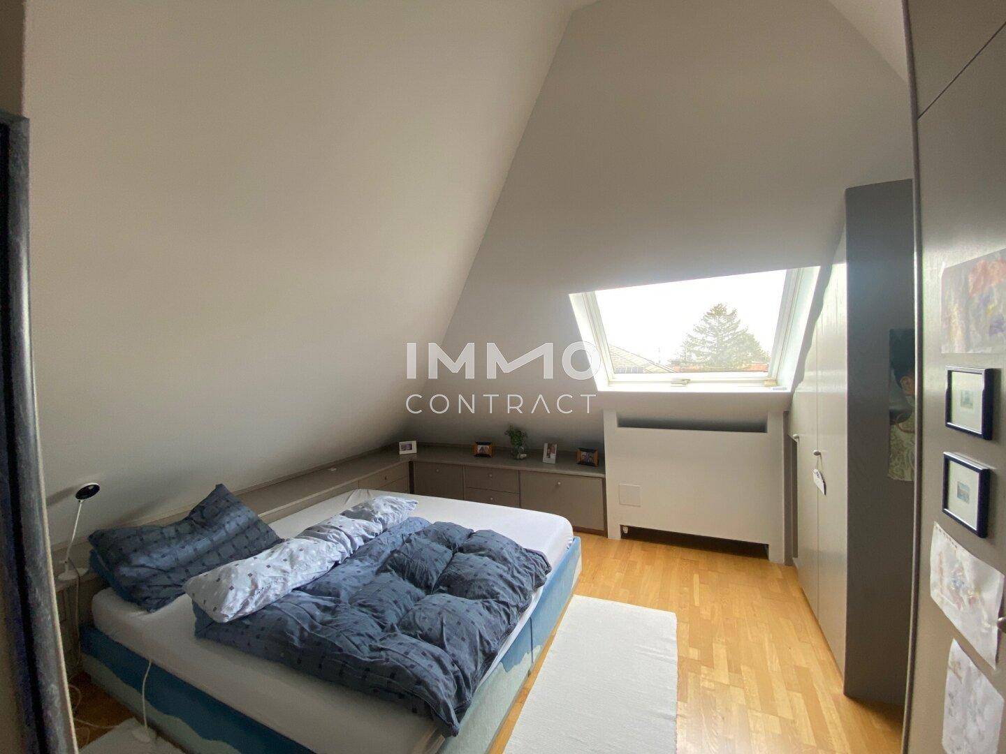 Schlafzimmer im Dachgeschoss mit schrägen Wänden, Dachfenster und Holzboden.