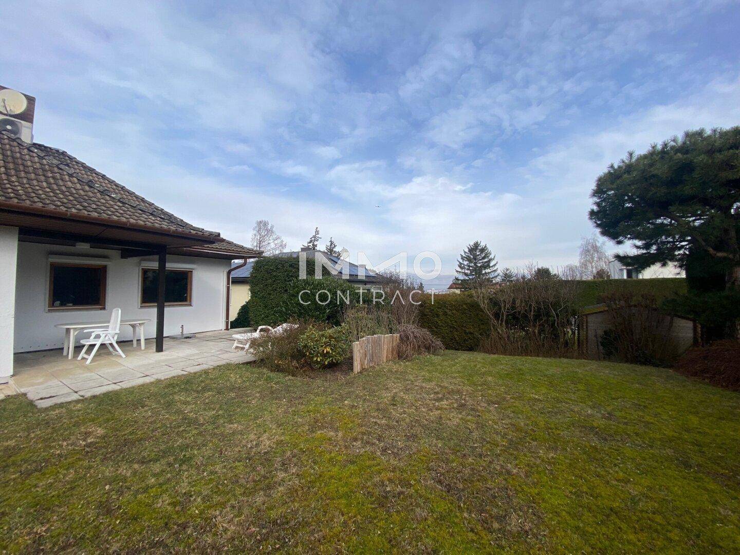 Rückansicht des Hauses mit großem Garten, Rasenfläche und gepflegten Büschen.