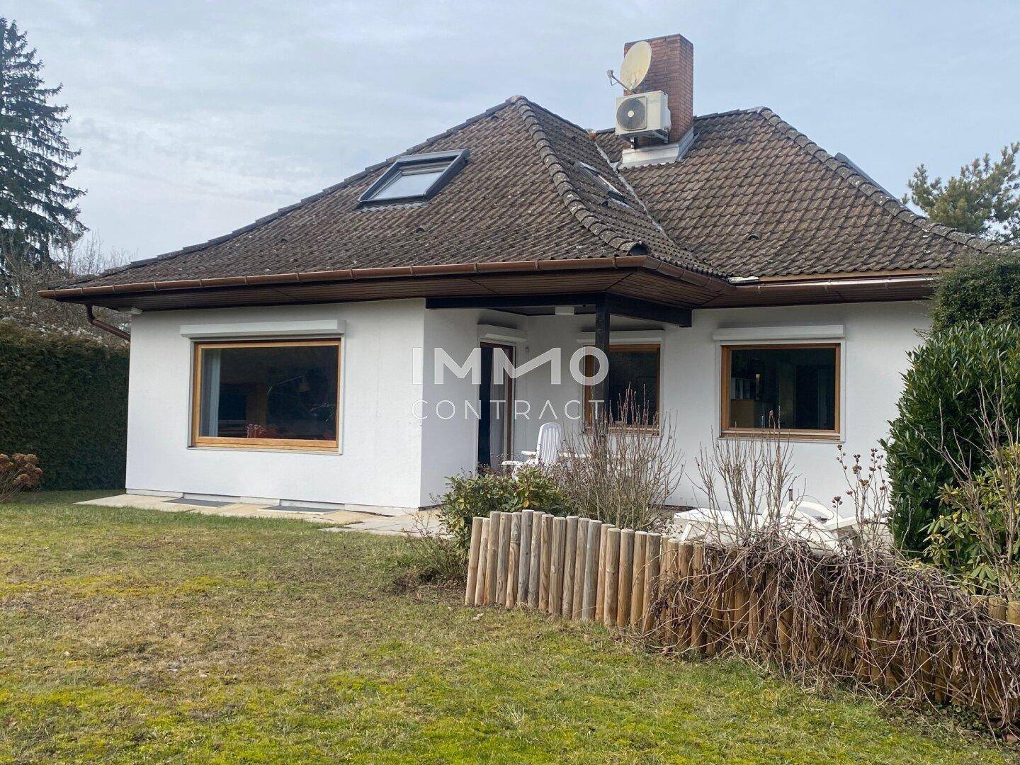 Rückansicht des Hauses mit großem Garten, Rasenfläche und gepflegten Büschen.