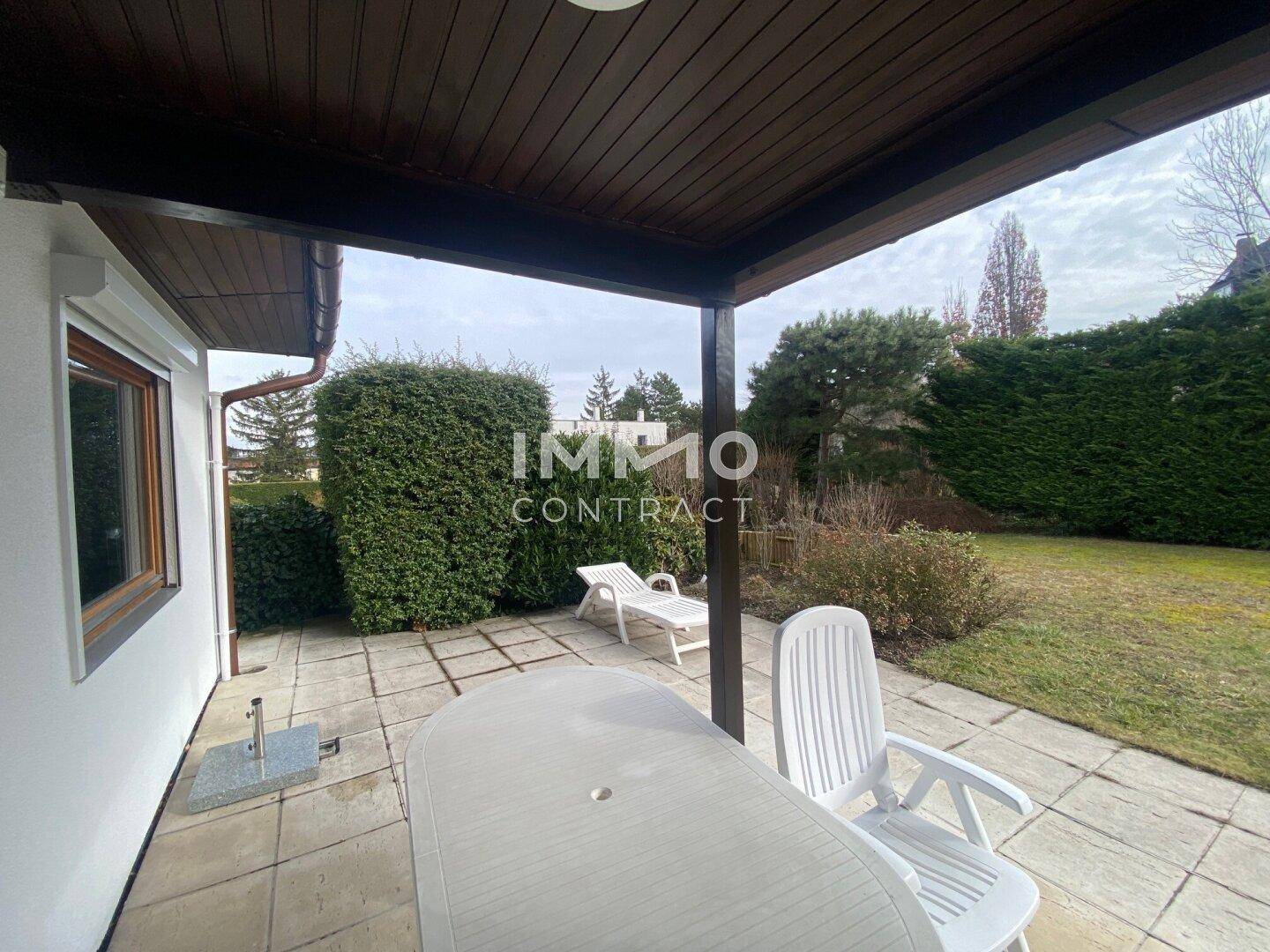 Überdachte Terrasse mit Gartenmöbeln und Blick auf den gepflegten Garten.