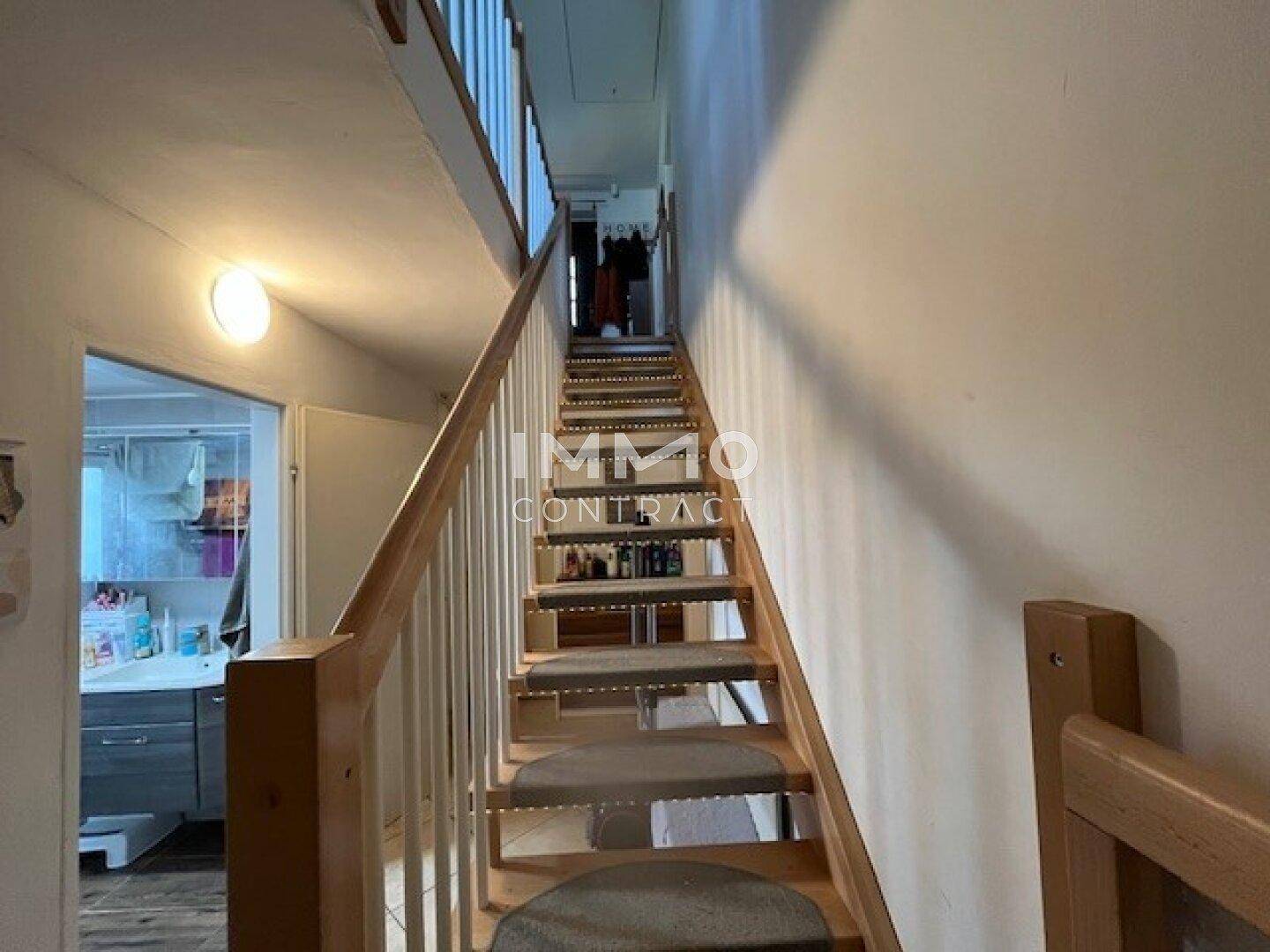 Helle Holztreppe mit Teppichstufen, die die verschiedenen Etagen des Hauses verbindet.