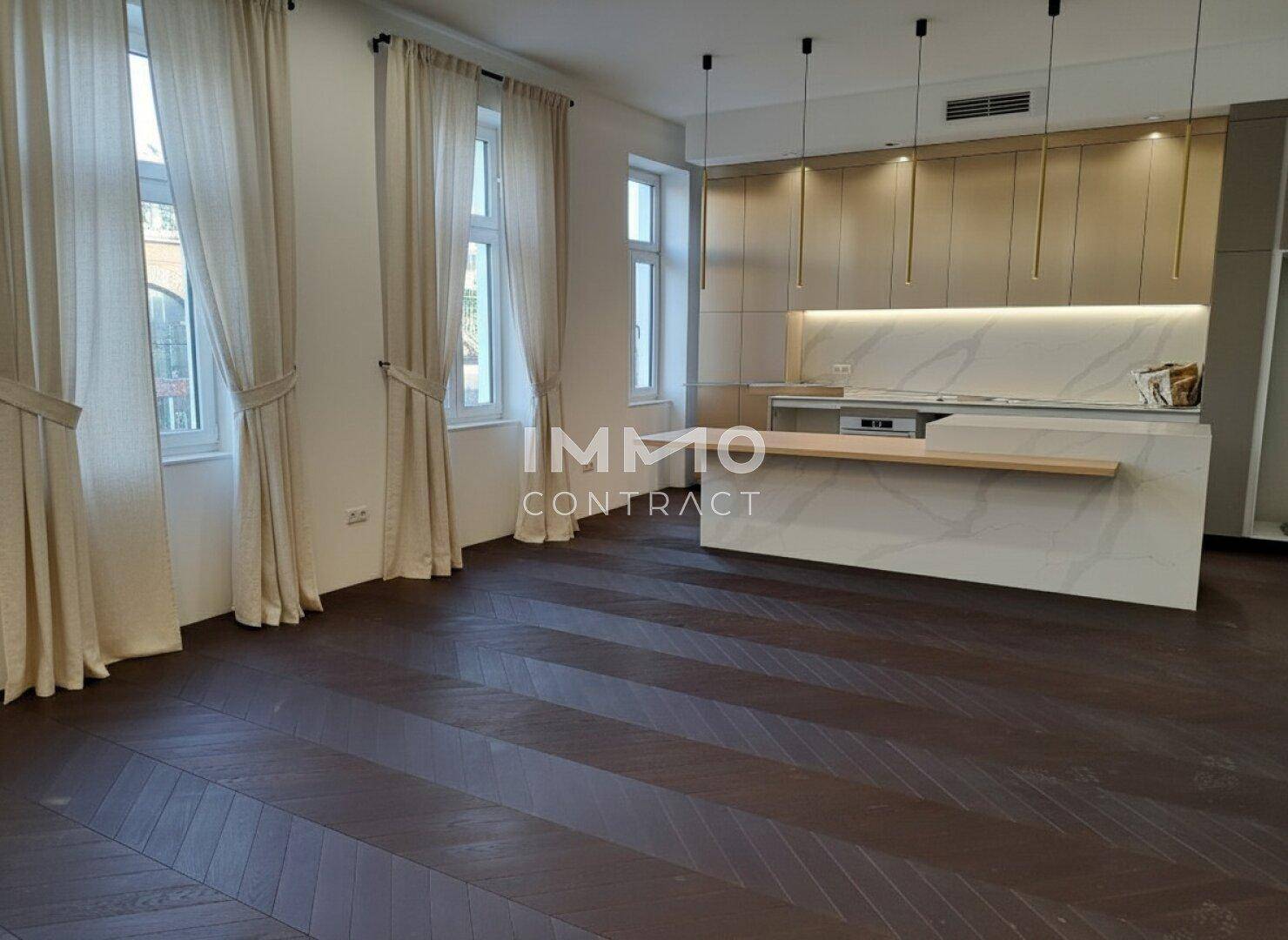 Helle, offene Küche mit moderner Ausstattung, Marmor-Arbeitsplatten und dunklem Fischgrätparkett.