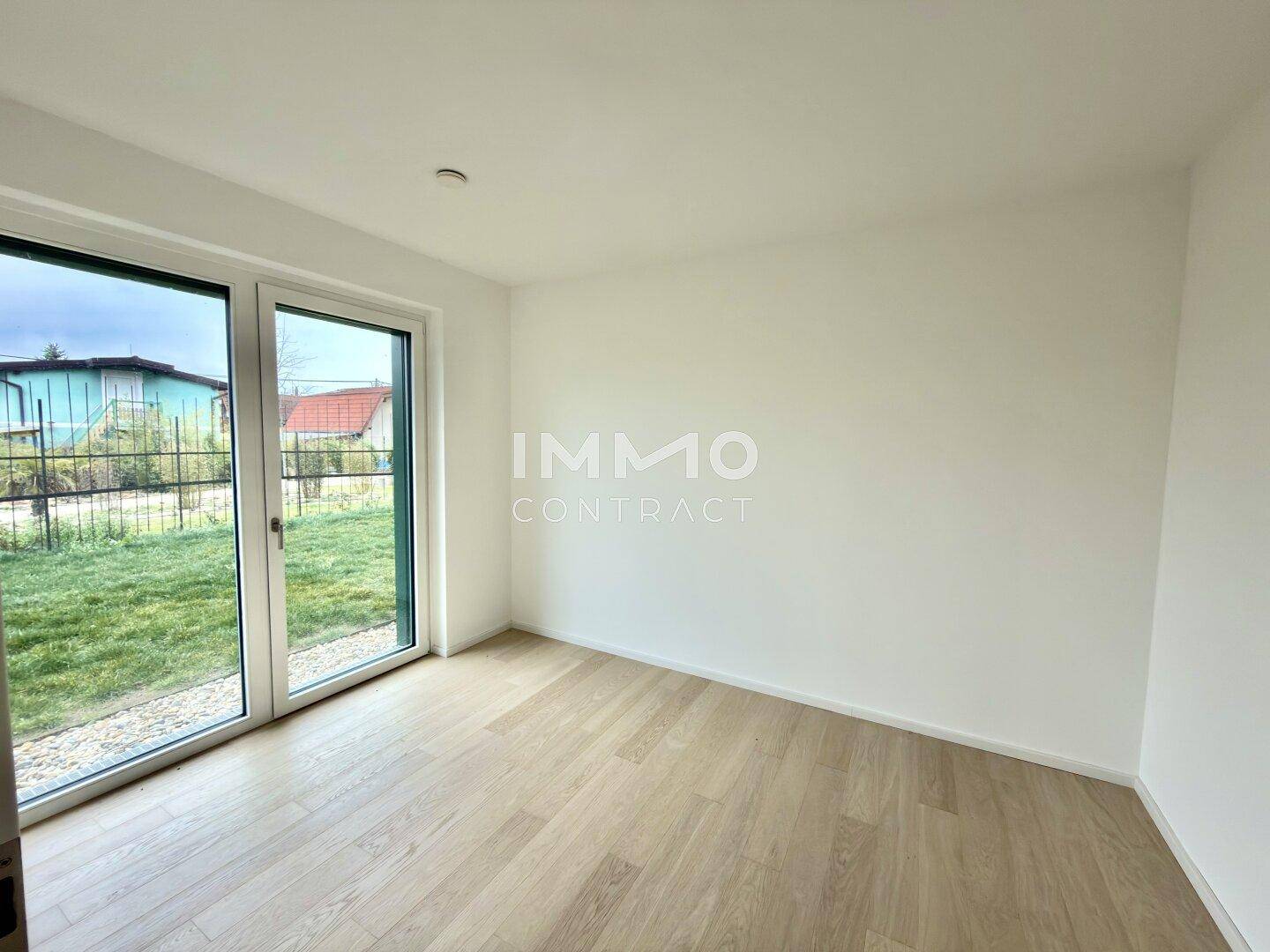 Heller, leerer Raum mit großen Fenstern und Blick ins Grüne, ideal für individuelle Gestaltung.