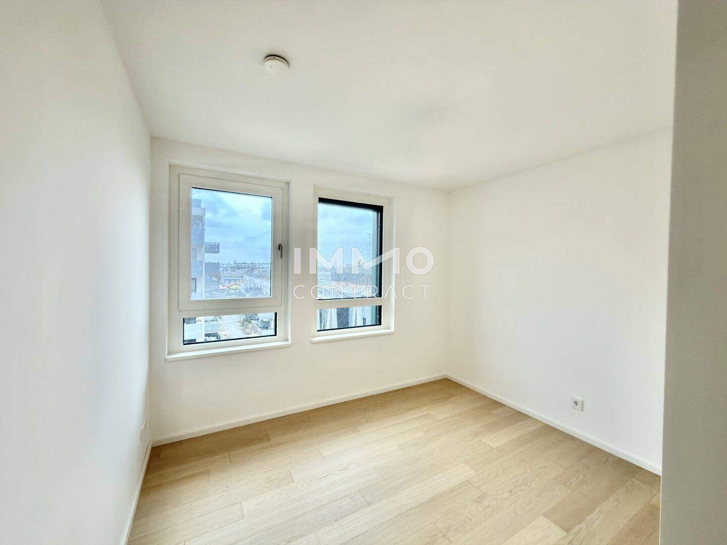 Helles Zimmer mit zwei Fenstern und Parkettboden, ideal als Schlaf- oder Arbeitszimmer.