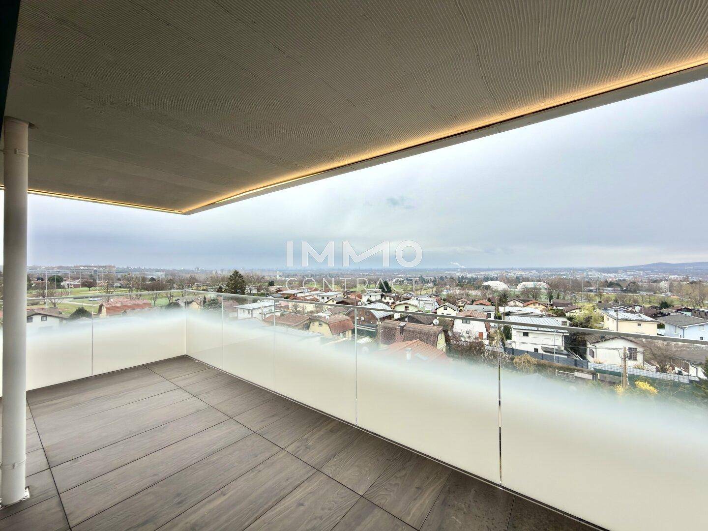 Geräumiger Balkon mit Fliesenboden und Glasgeländer, bietet einen weiten Blick über die Umgebung.