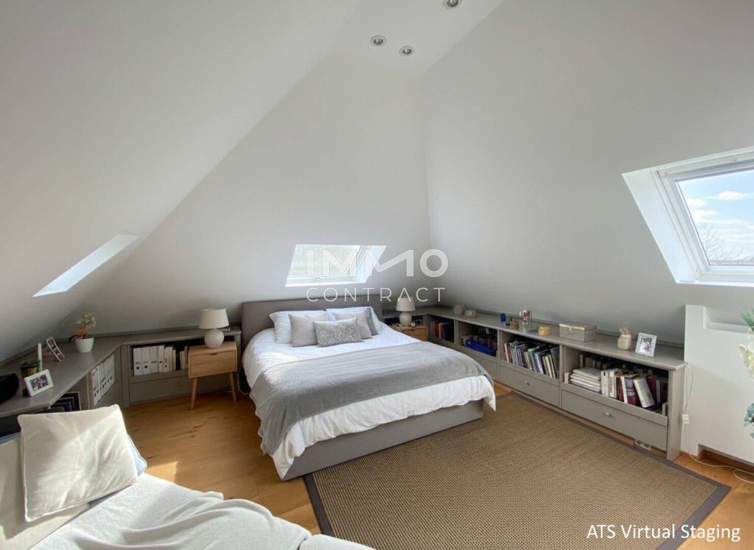 Geräumiges Schlafzimmer im Dachgeschoss mit Doppelbett, Bücherregalen und Holzboden.