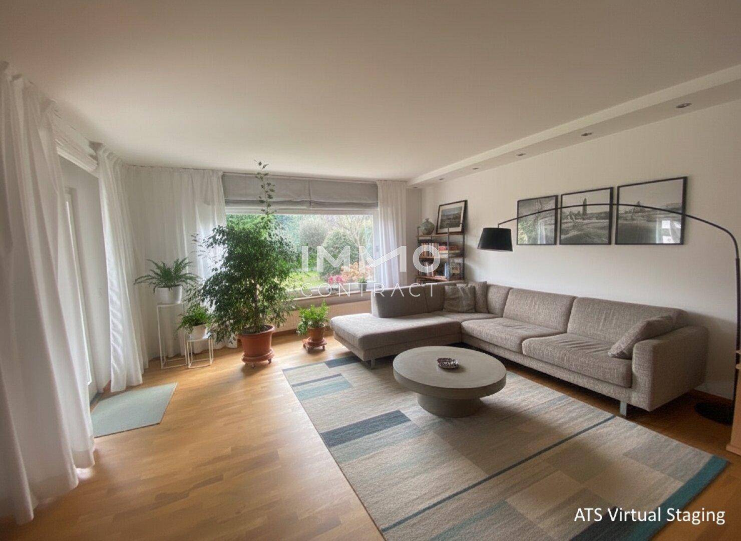 Modernes Wohnzimmer mit großem Ecksofa, Teppich und Blick in den grünen Garten.