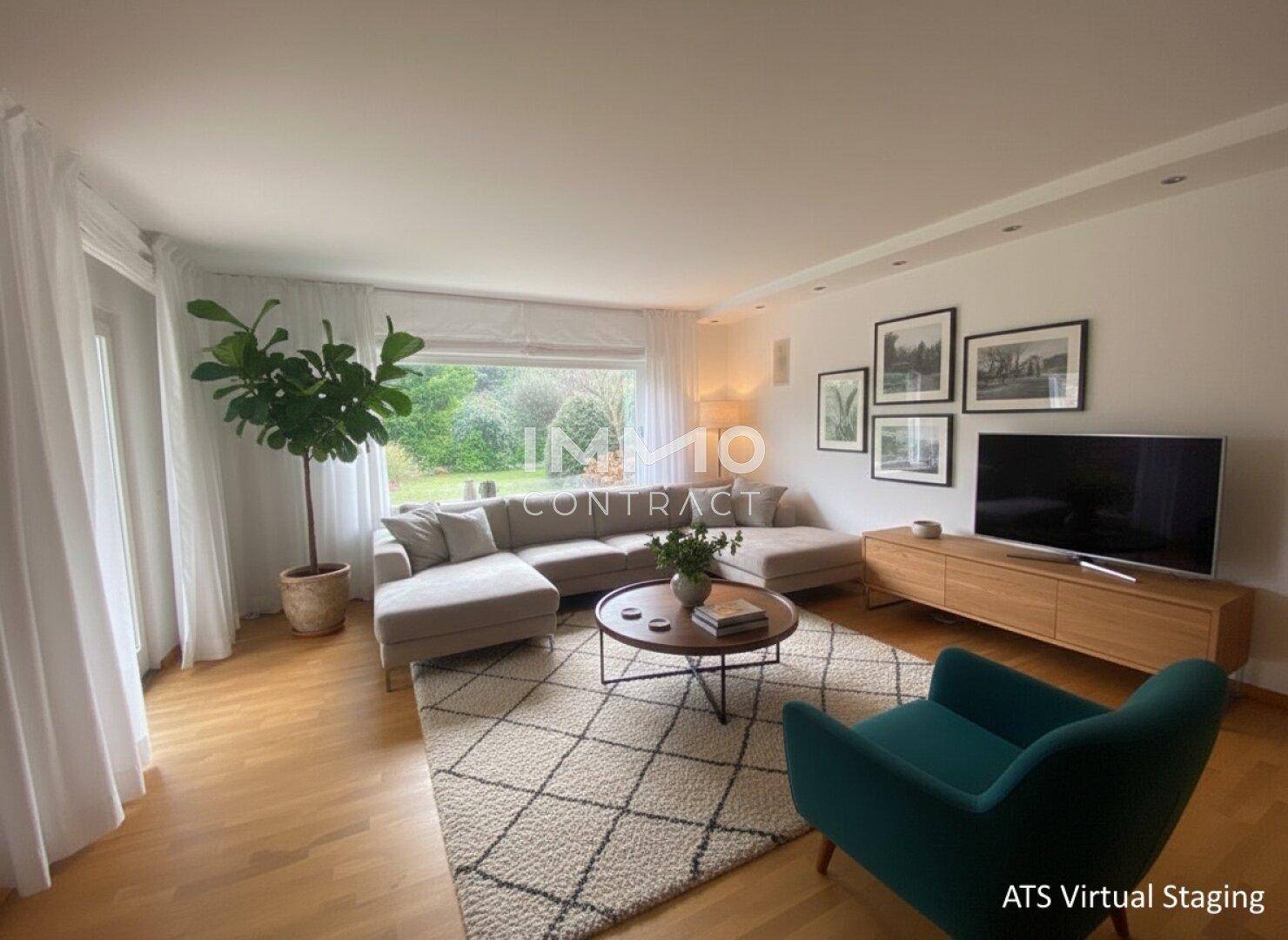Helles Wohnzimmer mit großem Ecksofa, Holzboden und Blick in den grünen Garten.