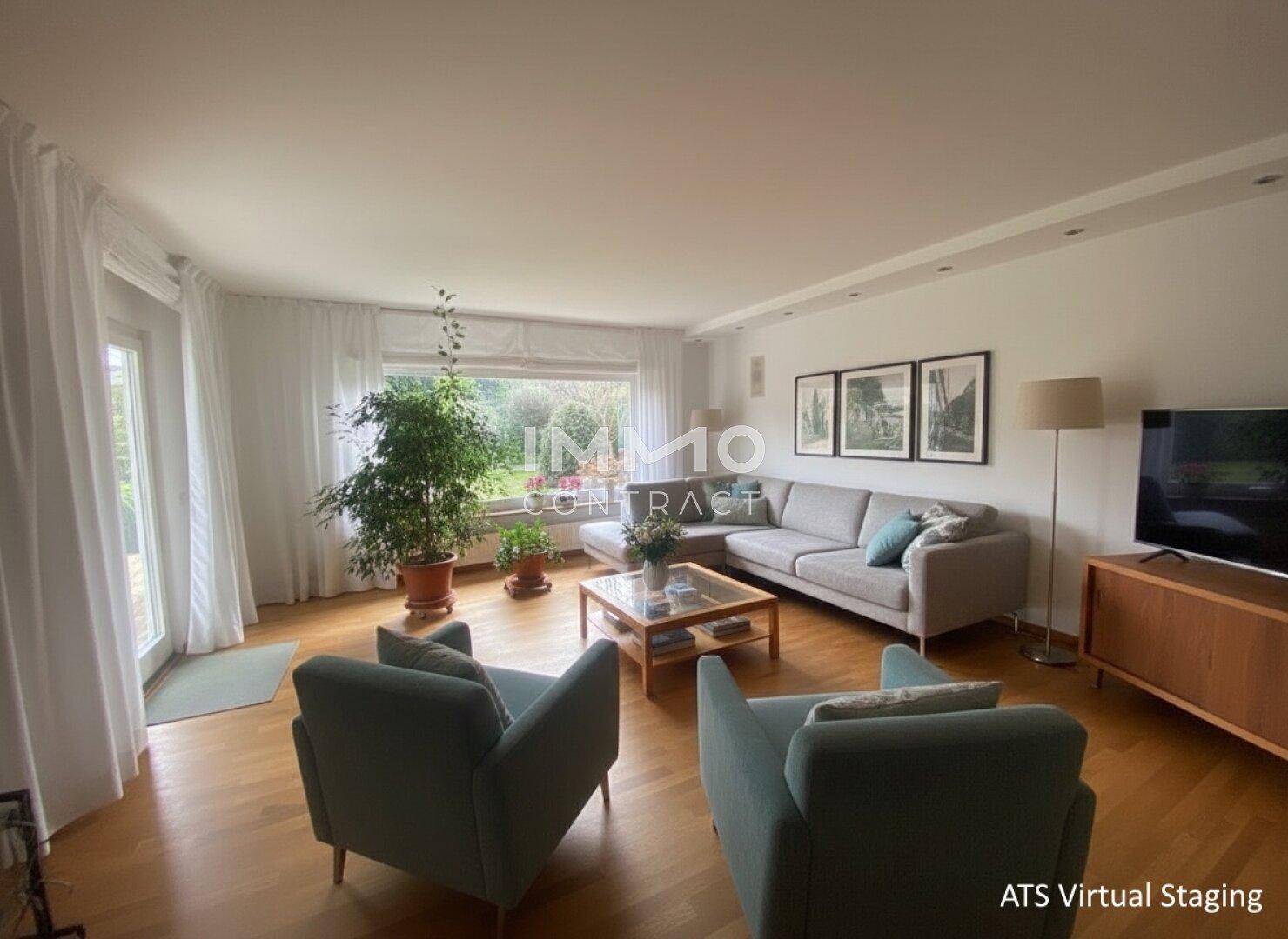 Helles Wohnzimmer mit bequemen Sofas, Holzboden und großen Fenstern zum Garten.