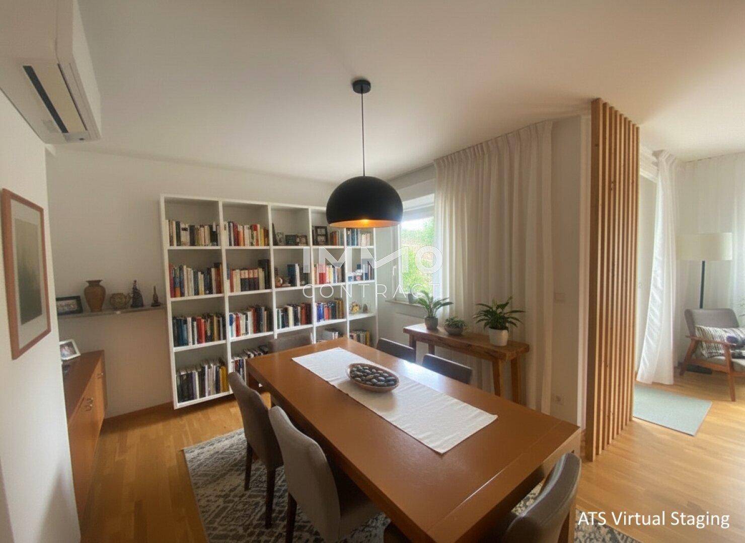 Heller Essbereich mit großem Holztisch, Bücherregal und Zugang zum Wohnzimmer.
