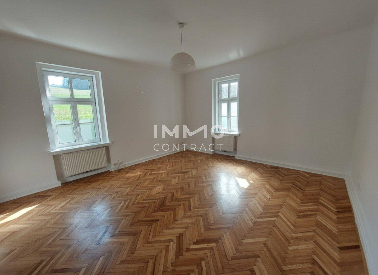 Geräumiges Wohnzimmer mit klassischem Parkettboden und viel Tageslicht.
