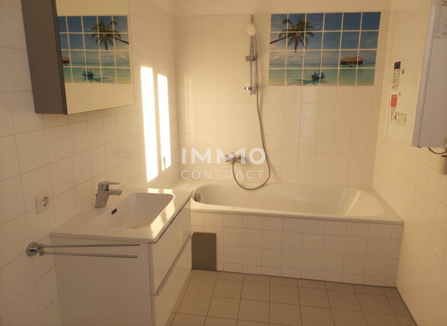 Badezimmer mit Badewanne, Waschbecken und hellen Fliesen.