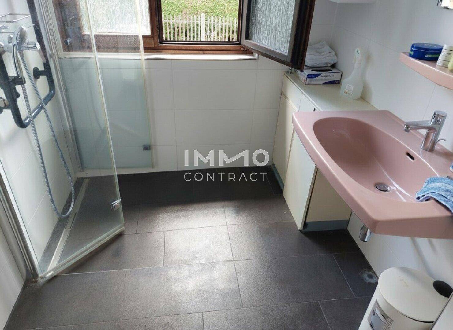 Funktionales Badezimmer mit Dusche, Waschbecken und Fenster, ausgestattet mit Haltegriffen.