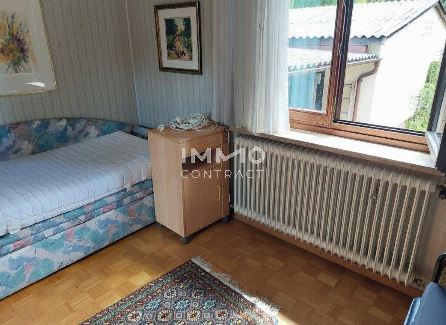Gemütliches Schlafzimmer mit Einzelbett, Nachttisch und Fenster für natürliche Belichtung.