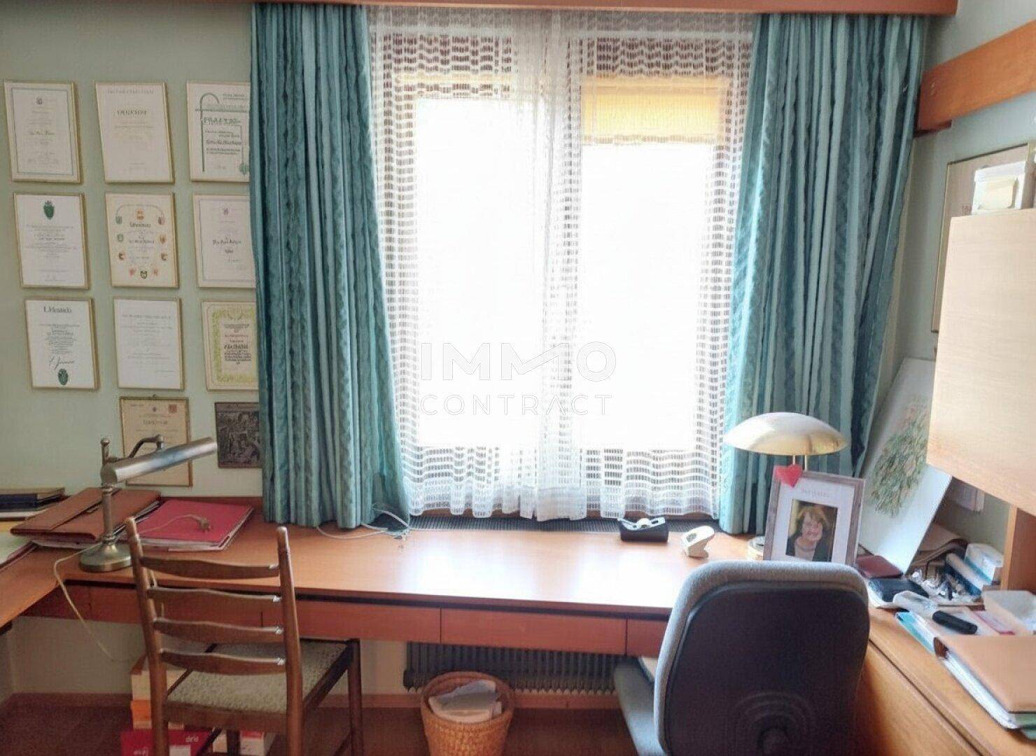 Geräumiges Büro mit großem Schreibtisch und breitem Fenster, das viel Tageslicht hereinlässt.