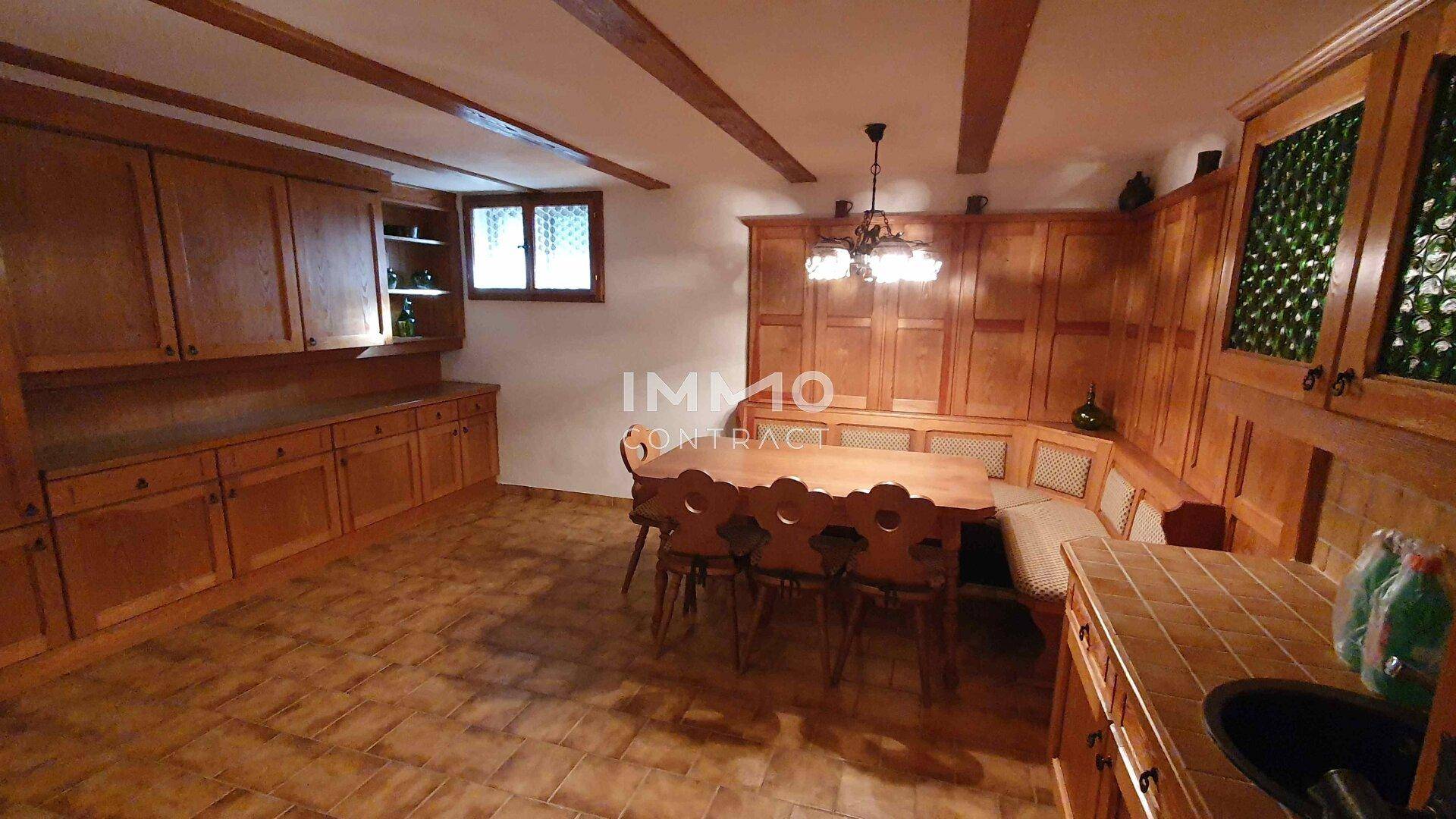 Rustikales Esszimmer im alpinen Stil mit Holztäfelung, sichtbaren Balken und einem großen Esstisch.