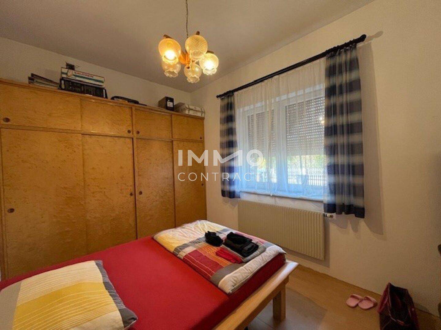 Schlafzimmer mit Holzboden, großem Kleiderschrank und Fenster mit Blick nach draußen.