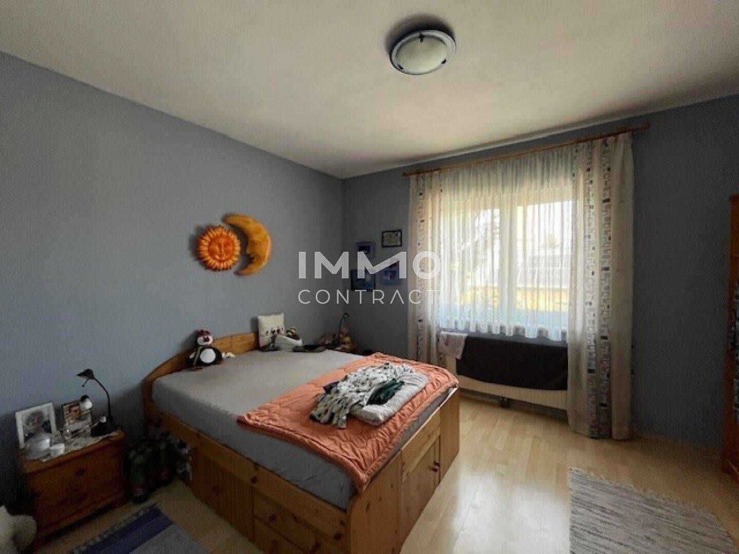 Schlafzimmer mit Holzbett, Parkettboden und blauen Wänden, bietet eine ruhige Atmosphäre.
