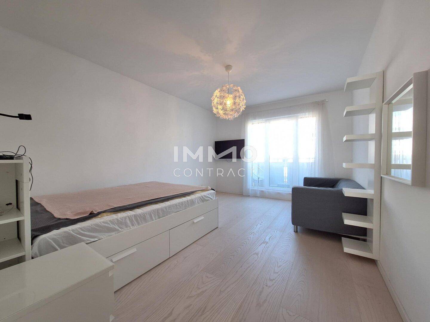 Helles Schlafzimmer mit Holzboden, Tagesbett und großem Fenster.