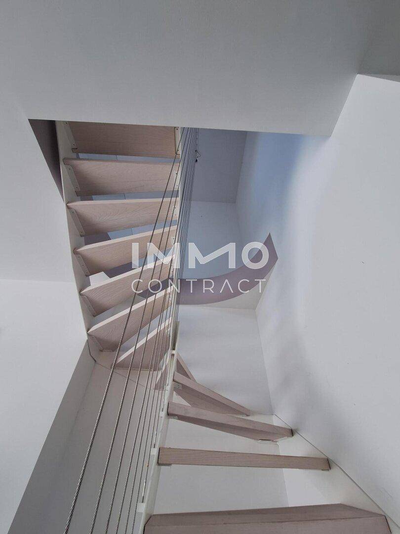 Elegante Wendeltreppe mit Holzstufen und modernen Geländerseilen.