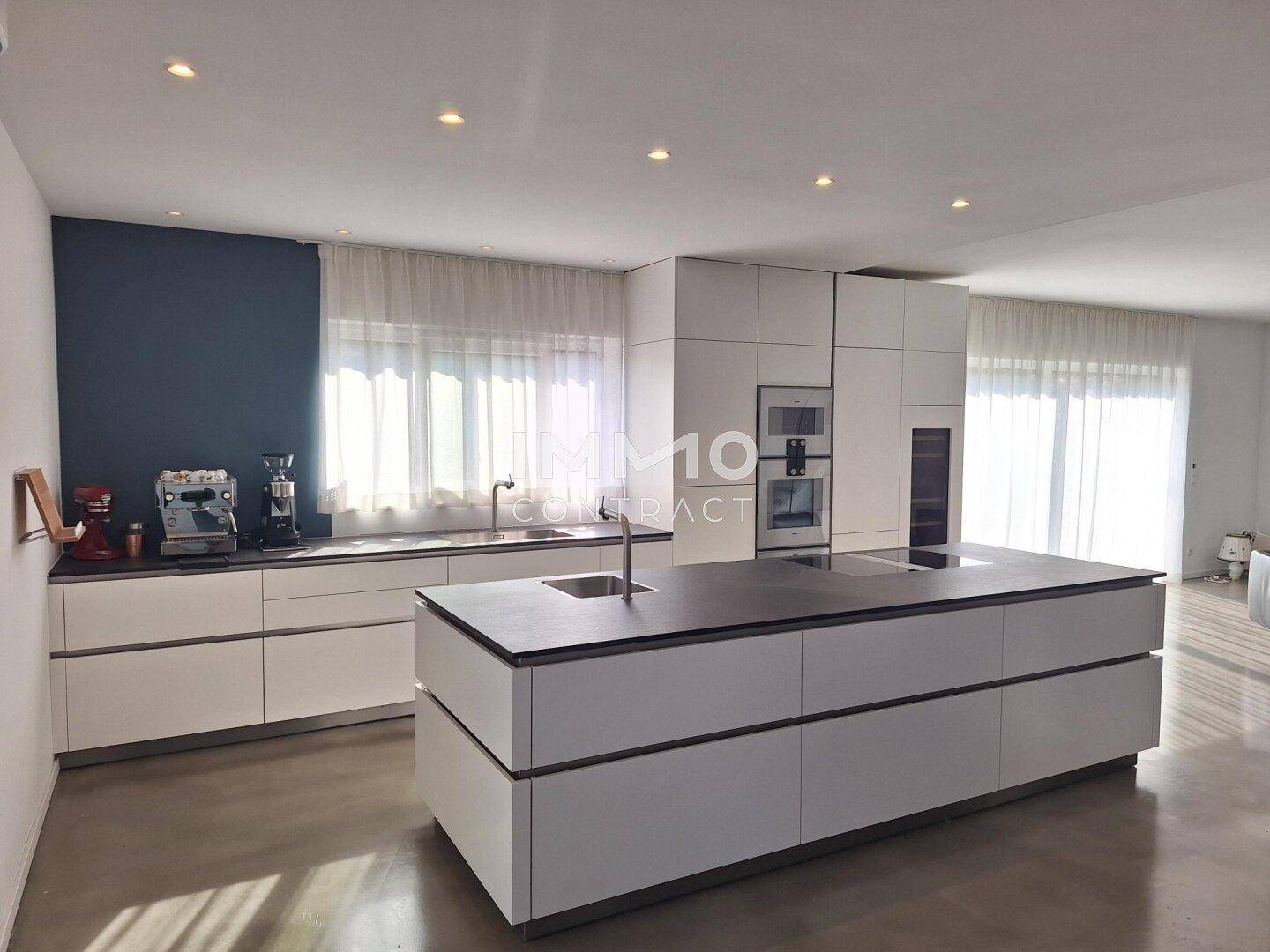 Moderne Einbauküche mit Kochinsel, weißen Schränken und integrierten Geräten.