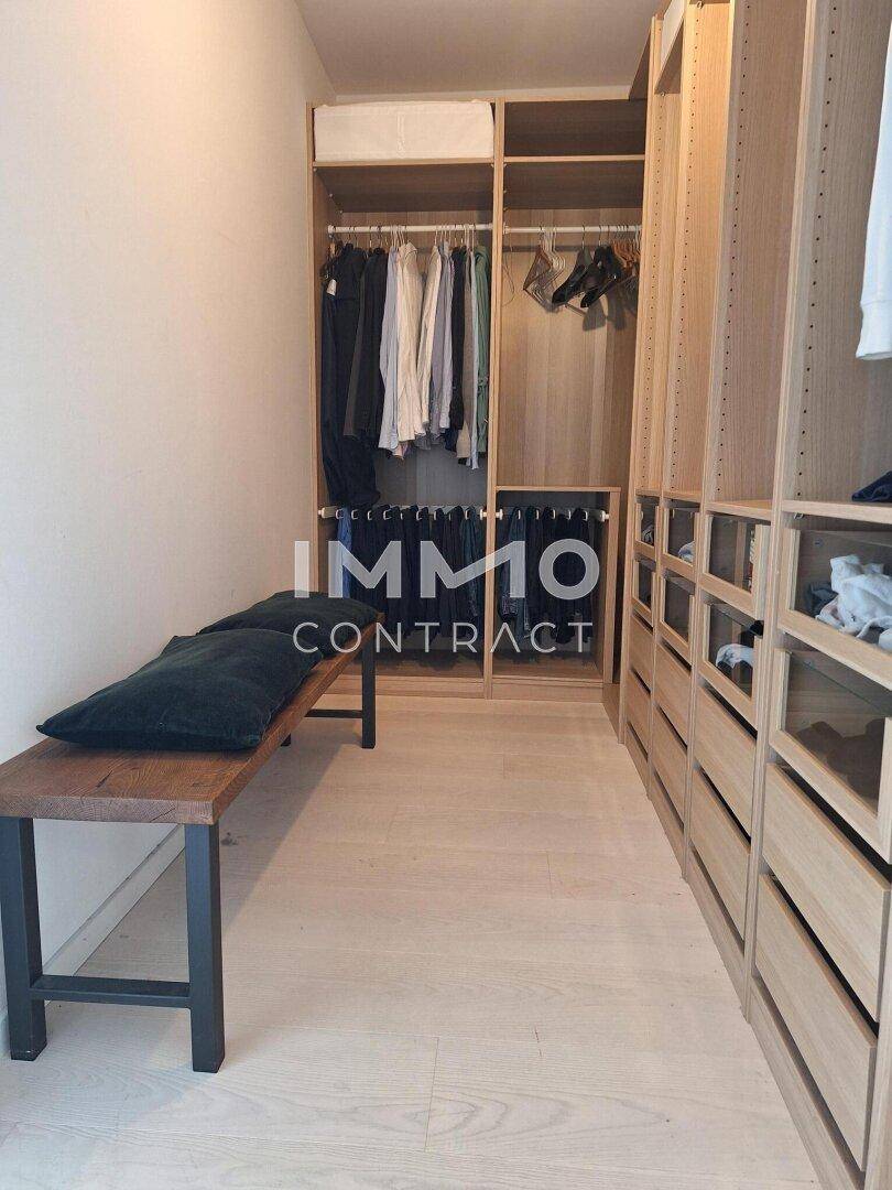 Geräumiger begehbarer Kleiderschrank mit Holzregalen und viel Stauraum.