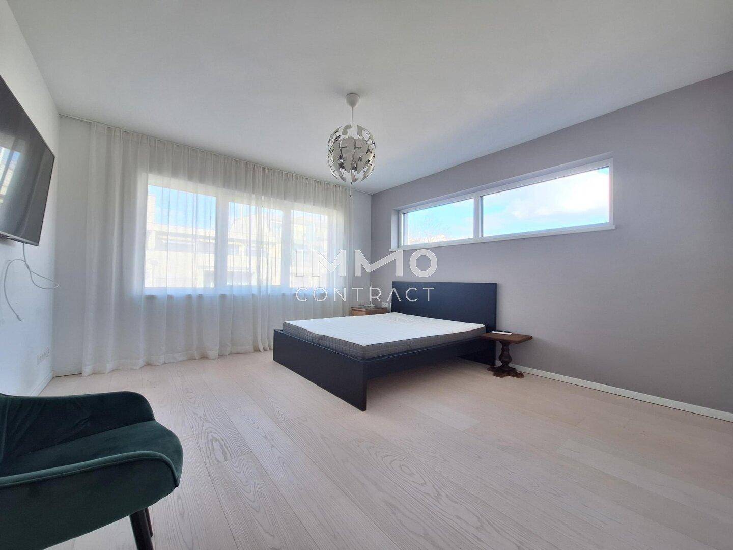 Modernes Schlafzimmer mit Holzboden, großzügigen Fenstern und minimalistischer Einrichtung.