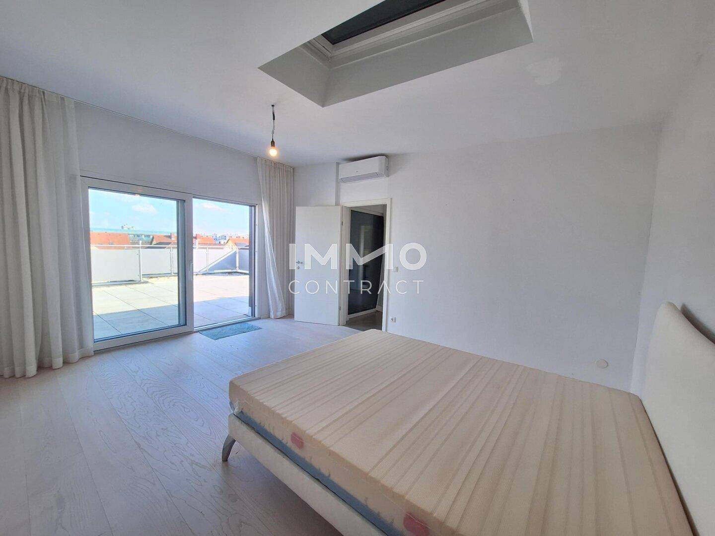 Helles Schlafzimmer mit Zugang zur Dachterrasse, Holzboden und Klimaanlage.