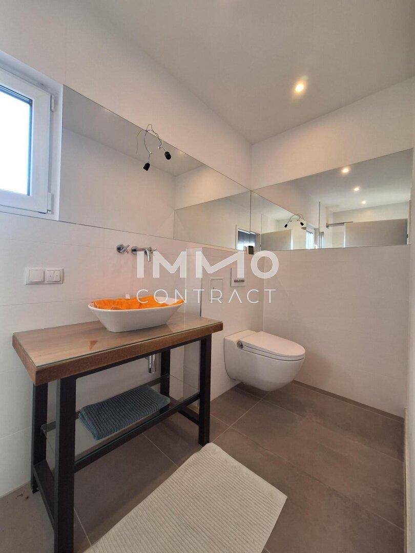 Modernes Badezimmer mit Aufsatzwaschbecken, großem Spiegel und Fenster.