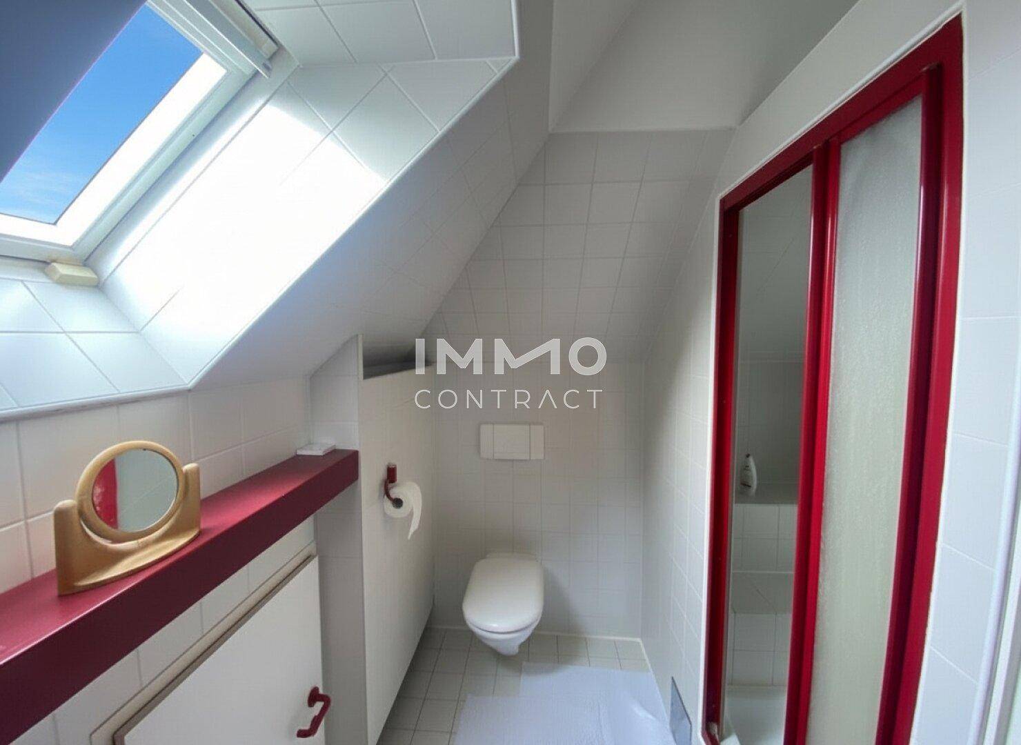 Modernes Badezimmer im Dachgeschoss mit Dusche, WC und Dachfenster für Tageslicht.