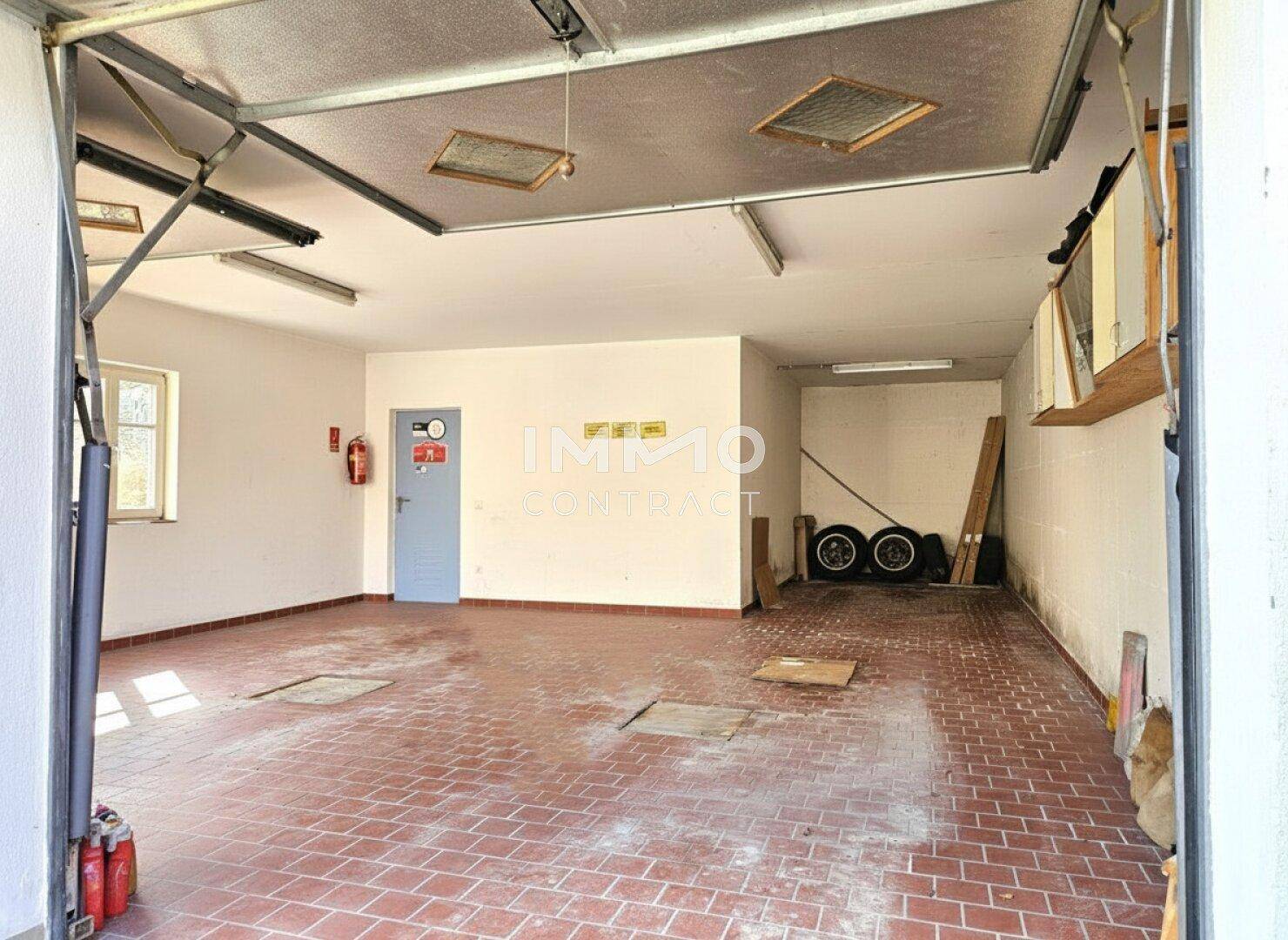 Geräumige Garage mit Fliesenboden und ausreichend Platz für Fahrzeuge und Lagerung.